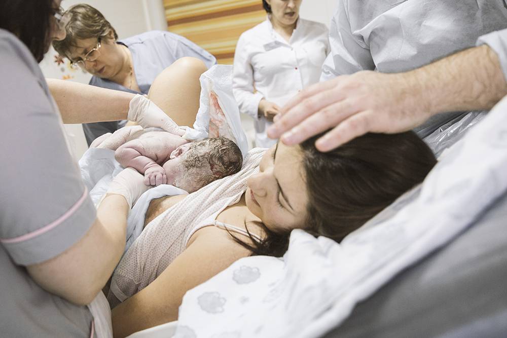 Женщина рожает дочку. Процесс рождения ребенка.